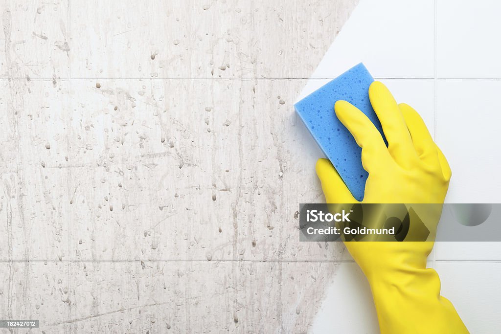 Cleaning Closeup of a hand in a yellow rubber glove cleaning a dirty bathroom surface with a blue sponge. Cleaning Stock Photo