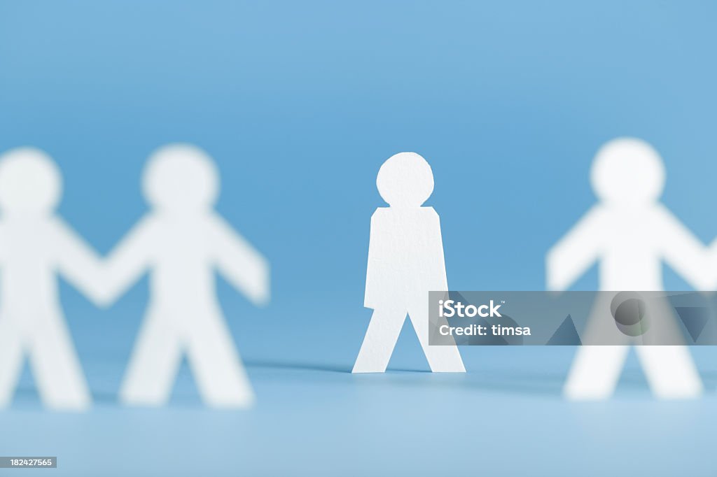 Paper figures holding hands with one alone not participating Paper person not participating in a group activity. On blue. Exclusion Stock Photo