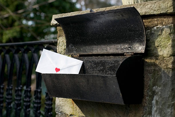 A white envelope with a red heart is in an old black metal mailbox. Selective focus on the envelope.see related: