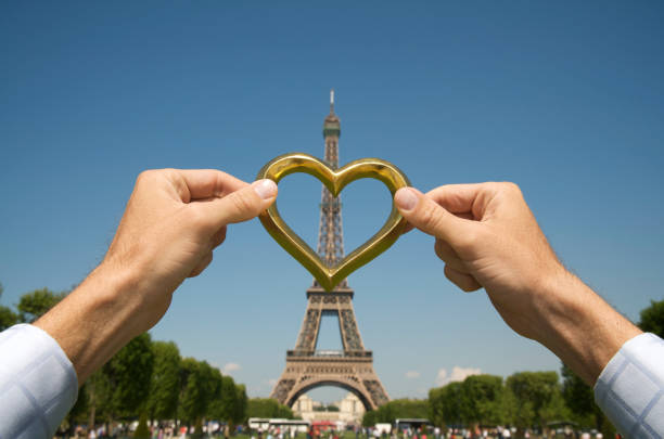 Hands Hold Golden Heart Against Eiffel Tower