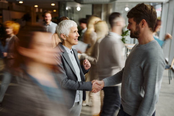 Happy entrepreneurs greeting among their colleagues in blurred motion.