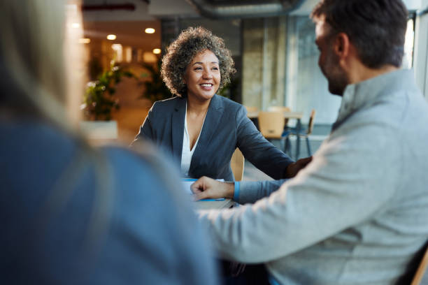 Feliz corretora de seguros conversando com seus clientes no escritório. - foto de acervo