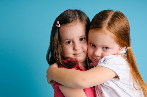 Color photo of two happy three-year-old friends giving each other a hug.