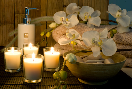 health spa setting with towels, candle and flowers, candlelit.