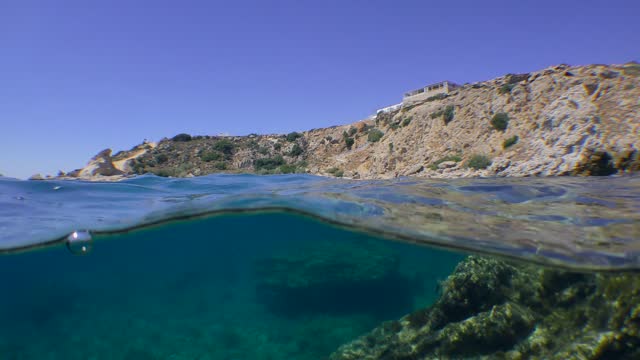 Split, a camera at sea level at the same time shows an underwater and surface rocky coastal landscape.