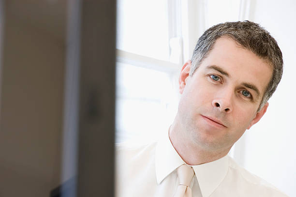 Thoughtful businessman,peering past his computer stock photo