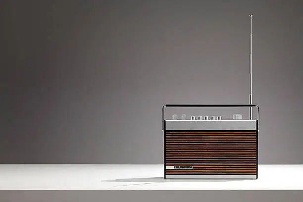 "Old, retro radio on a white table.Speakers covered by wood. Very stylish radio!"