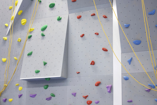 indoor climbing wall with ropes and colored climbing grips