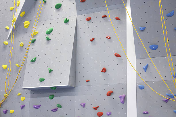 Indoor climbing wall with grips indoor climbing wall with ropes and colored climbing grips crag stock pictures, royalty-free photos & images