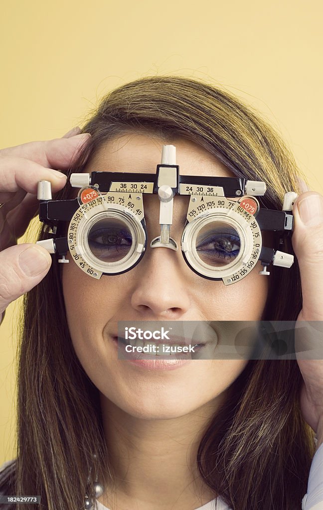 Optometrist Eye Exam Trial Frames Optometrist examines the eyes of a young woman patient with trial frames. Male hands adjusting dial on the trial frames. 25-29 Years Stock Photo