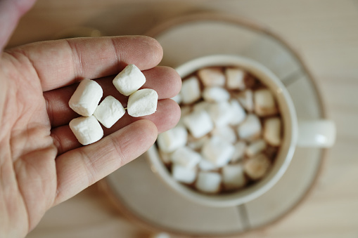 Adding marshmallows on a hot chocolate mug