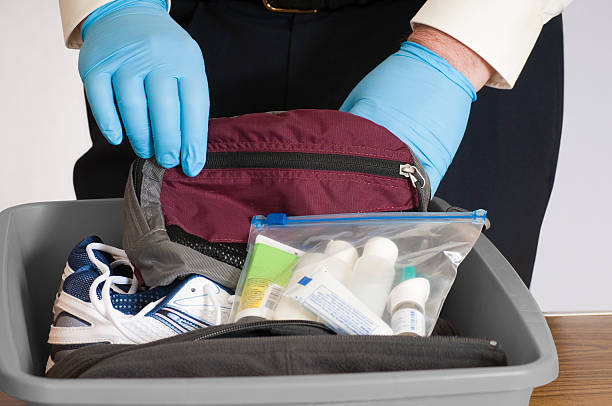 Airport Security Baggage Search "Gloved hands of an airport security person examining the contents of a bin with a traveler's fanny pack, shoes, sweater, and allowable liquids.Click below for others in this series and all my airport related images:" customs official photos stock pictures, royalty-free photos & images