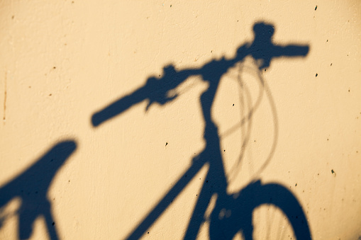 The blue shadow of a bicycle against a pock-marked concrete wall.  Cross Processed.