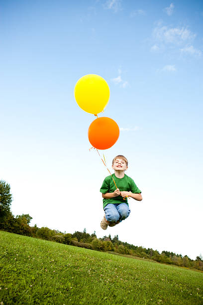 istock Happy Young Boy Jumping with Balloons Outside 182430263