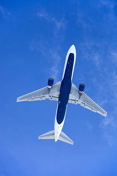 avion à réaction au-dessus de contre un ciel bleu clair - underbelly photos et images de collection