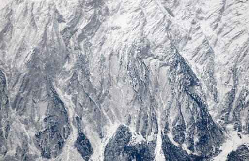 A scenic view of a rocky mountain range covered with forest in grayscale