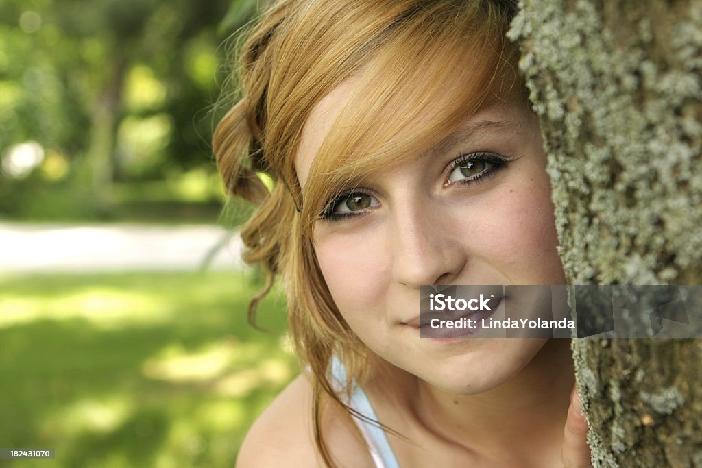 Beautiful Teen Girl A portrait of a pretty 14-15 year old girl peeking from behind a tree. Shallow DOF. Please view many other teen portraits in my portfolio. 14-15 Years Stock Photo