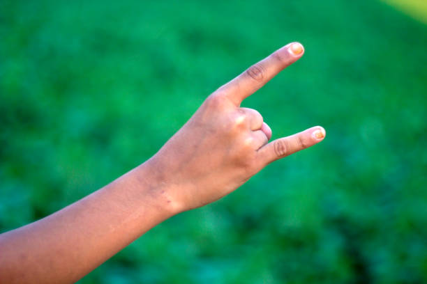 A man pointing two fingers of his hand forward and green background