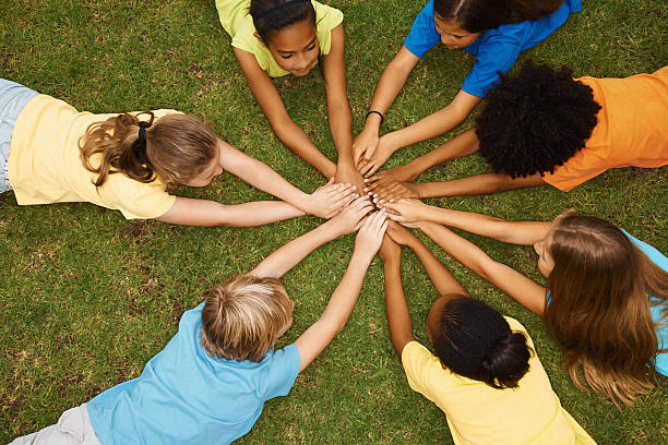 istock Children lying in a circle with their hands together 182431152