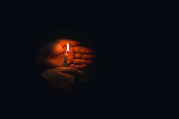 świeca w dłoniach. mężczyzna trzyma płonącą świecę na ciemnym tle. koncepcja religijna. miejsce na kopię. - handsman zdjęcia i obrazy z banku zdjęć