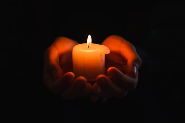 istock boy holds in a hand a burning candle against black background.Religious concept. 1824312131
