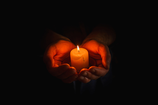 Religion concept.Concentration time.Remembrance of the dead.burning candle in a mans hand on dark background.