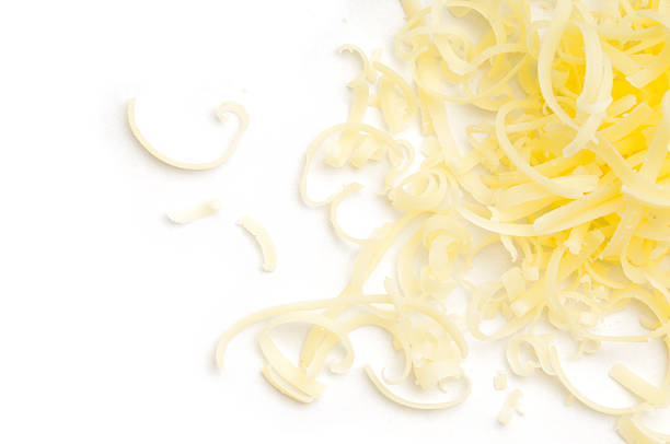 Grated Cheese Scattered Grated Chedder cheese scattered across a white background. white cheese stock pictures, royalty-free photos & images