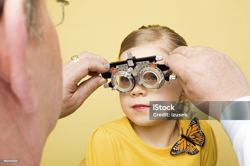 Optometrist Eye Exam Trial Frames Optometrist examines the eyes of a little girl patient with trial frames. 55-59 Years Stock Photo