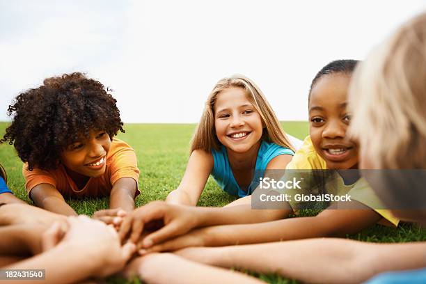 Niños Lying On Grass Con Sus Manos Juntas Foto de stock y más banco de imágenes de 10-11 años - 10-11 años, 8-9 años, Acostado