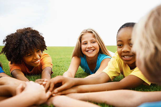 istock Children lying on grass with their hands together 182431540