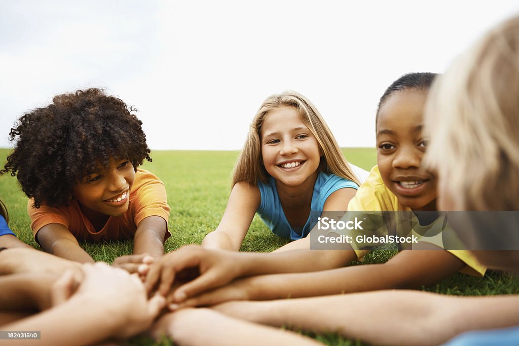 Crianças deitado na grama com suas mãos juntas - Foto de stock de 10-11 Anos royalty-free
