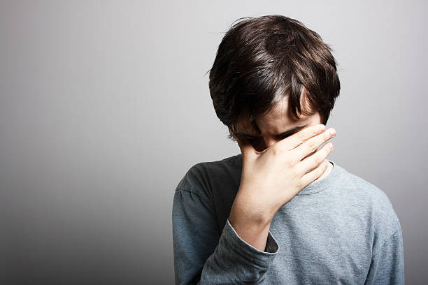 Depression "Young male with head in his hand, sombre tone." facepalm stock pictures, royalty-free photos & images