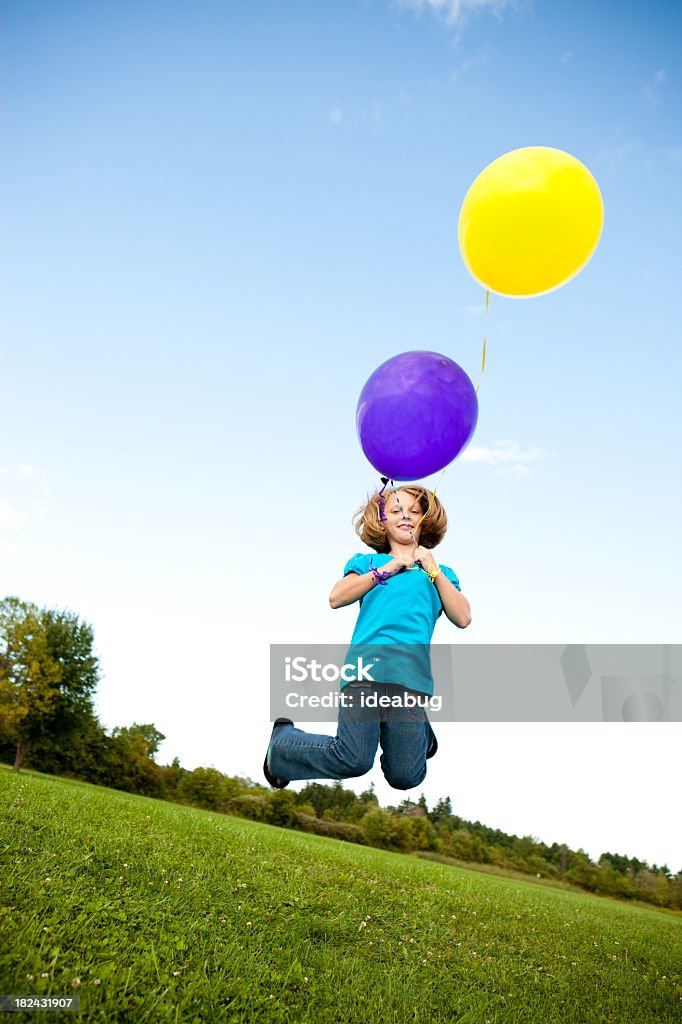 Jeune fille heureuse de sauter avec ballons à l'extérieur - Photo de 8-9 ans libre de droits