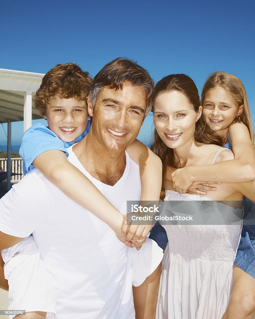 Portrait of parents piggybacking their kids Portrait of a happy parent piggybacking their kids against blue sky 25-29 Years Stock Photo