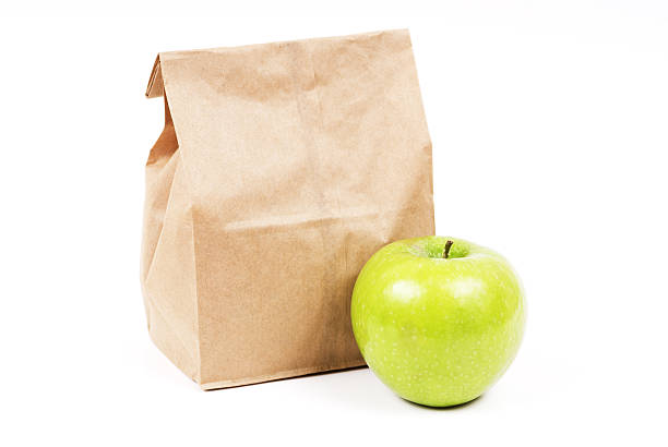 istock A brown paper bag containing lunch next to an apple 182432451