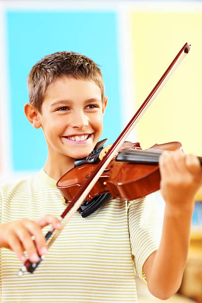 istock Cheerful talented young school boy playing the violin 182432684