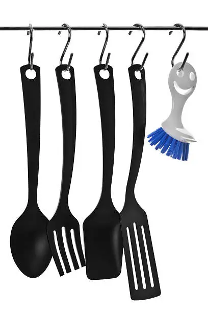 Cooking utensils hanging from hooks with dishbrush