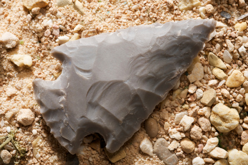 Native American arrowhead in sandy soil.