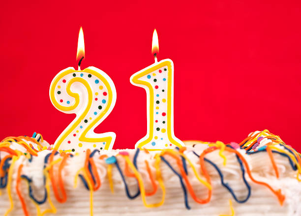 istock Decorated birthday cake with number 21 burning candles. Red background. 182433072