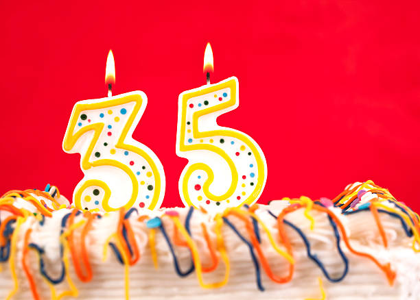 istock Decorated birthday cake with number 35 burning candles. Red background. 182433075