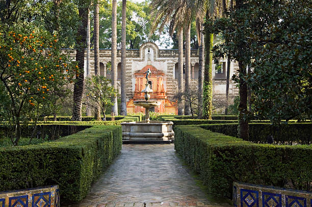 Alcazar Gardens Seville "The beautiful gardens of the Alcazar in Seville, Spain. The Alcazar, was originally a Royal Palace, and is one of the best remaining examples of Mudejar architecture. The upper levels of the palace which look out over the gardens, are still in use by the Royal Family when in residence ion Seville. The gardens are the largest late medieval gardens in Europe. ." sevilla province stock pictures, royalty-free photos & images
