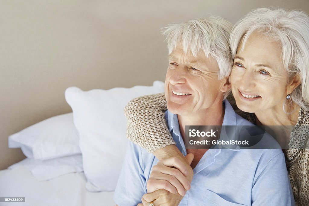Anziana coppia seduta insieme su un letto e guarda lontano - Foto stock royalty-free di 60-64 anni