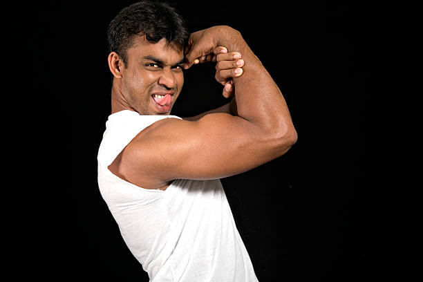 An in your face shot with plenty of copy space with an angry young man poking out his tongue as he aggressively flexes his arm and engages the camera.  Canon Eos 5D. Discover more in