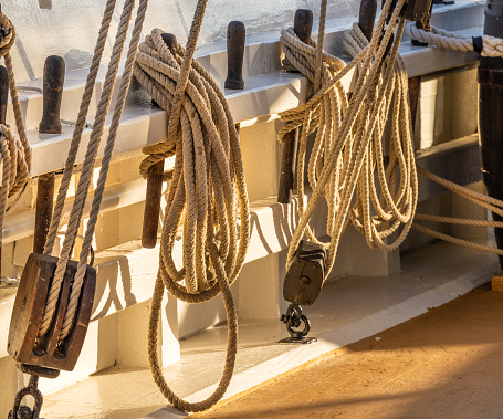 Secured ropes, hoists and pulleys on deck of historical schooner in sunset light