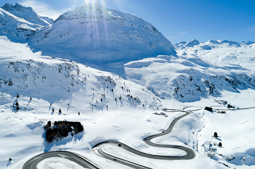 Aerial view of winding pass among snow-covered mountains in the Swiss Alps in winter.