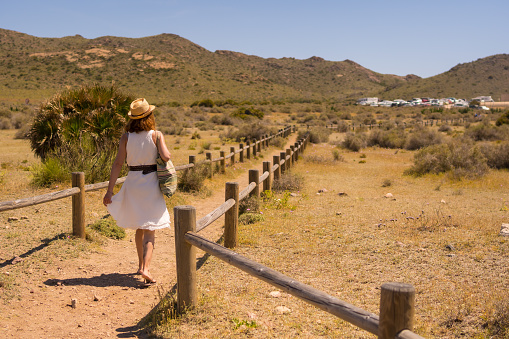 Woman walking along a path amidst wooden posts in Cabo de Gata, Spain