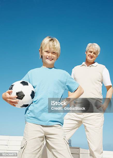 Ragazzo Con Un Pallone Da Calcio Con Nonno In Background - Fotografie stock e altre immagini di 60-64 anni