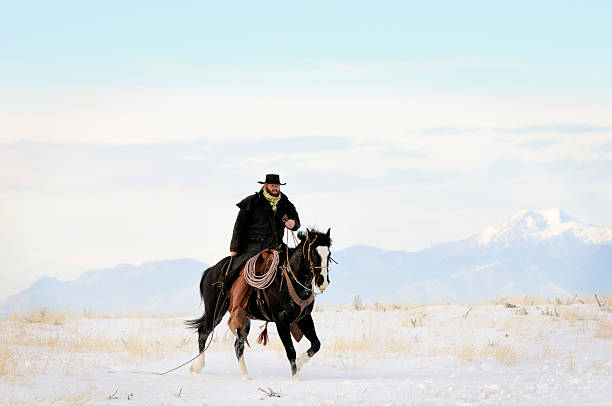 Hard Riding Cowboy In Action On Snowy Desert Landscape stock photo