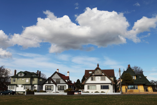 a row of residential houses with a puffy cloud overhead.