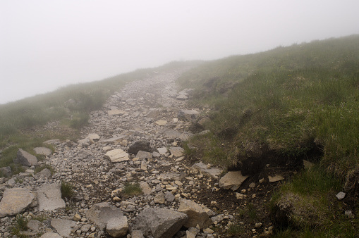 Rocky path at Plomb du Cantal in the clouds. Walking in poor visibility